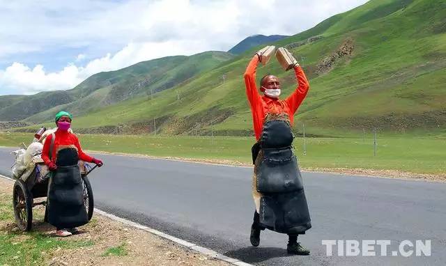 他们拉着板车带着食物三步一拜去朝圣